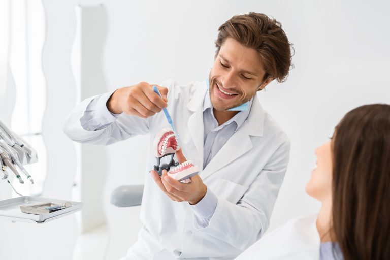 Handsome Dentist Showing How To Brush Teeth On Jaw Model
